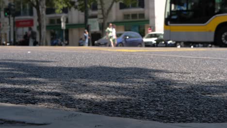 asphalt focus on foreground, blurred trafic and people in background, slow motion