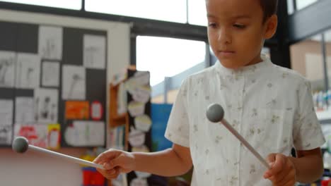 vista frontal de un escolar asiático tocando el xilófono en un aula de la escuela 4k