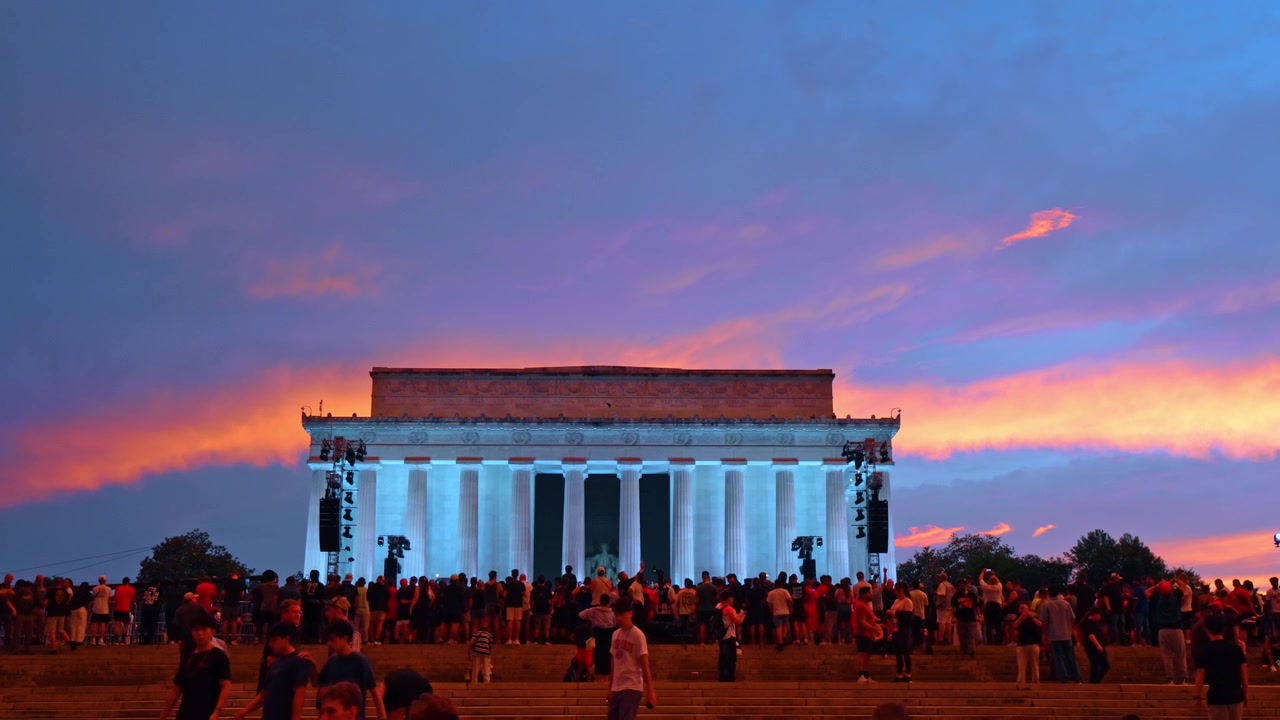 Washington, Hoa Kỳ, ngày 13 tháng 6 năm 2026: Đài tưởng niệm Lincoln được chiếu sáng nổi bật trên nền trời hoàng hôn. Các cột được chiếu sáng màu trắng và xanh lam với những đám mây màu cam, hồng và tím rực rỡ phía sau mặt tiền.