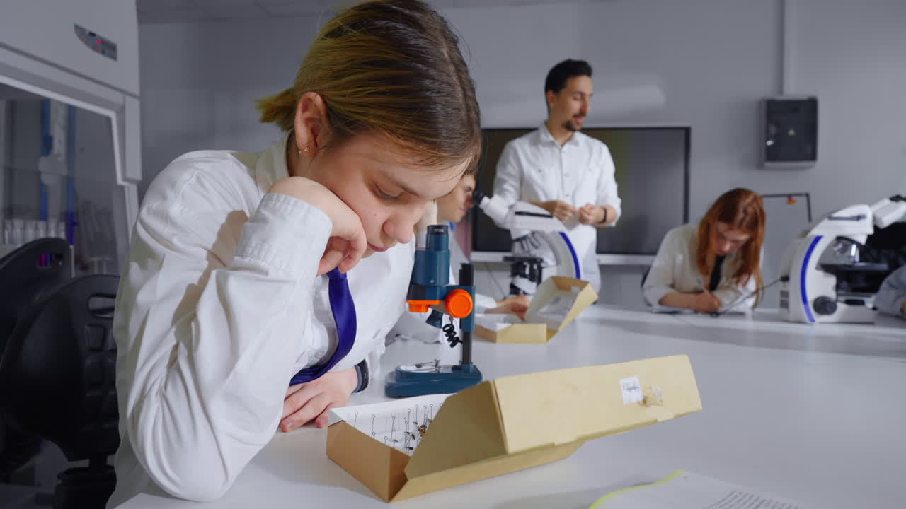 과학 실험실 의 학생 들 이 현미경 아래 표본 을 보고 있다
