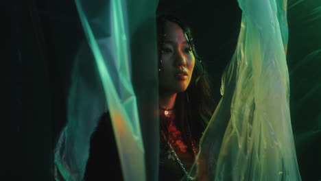 amazed woman walking through cellophane curtains in studio with neon light