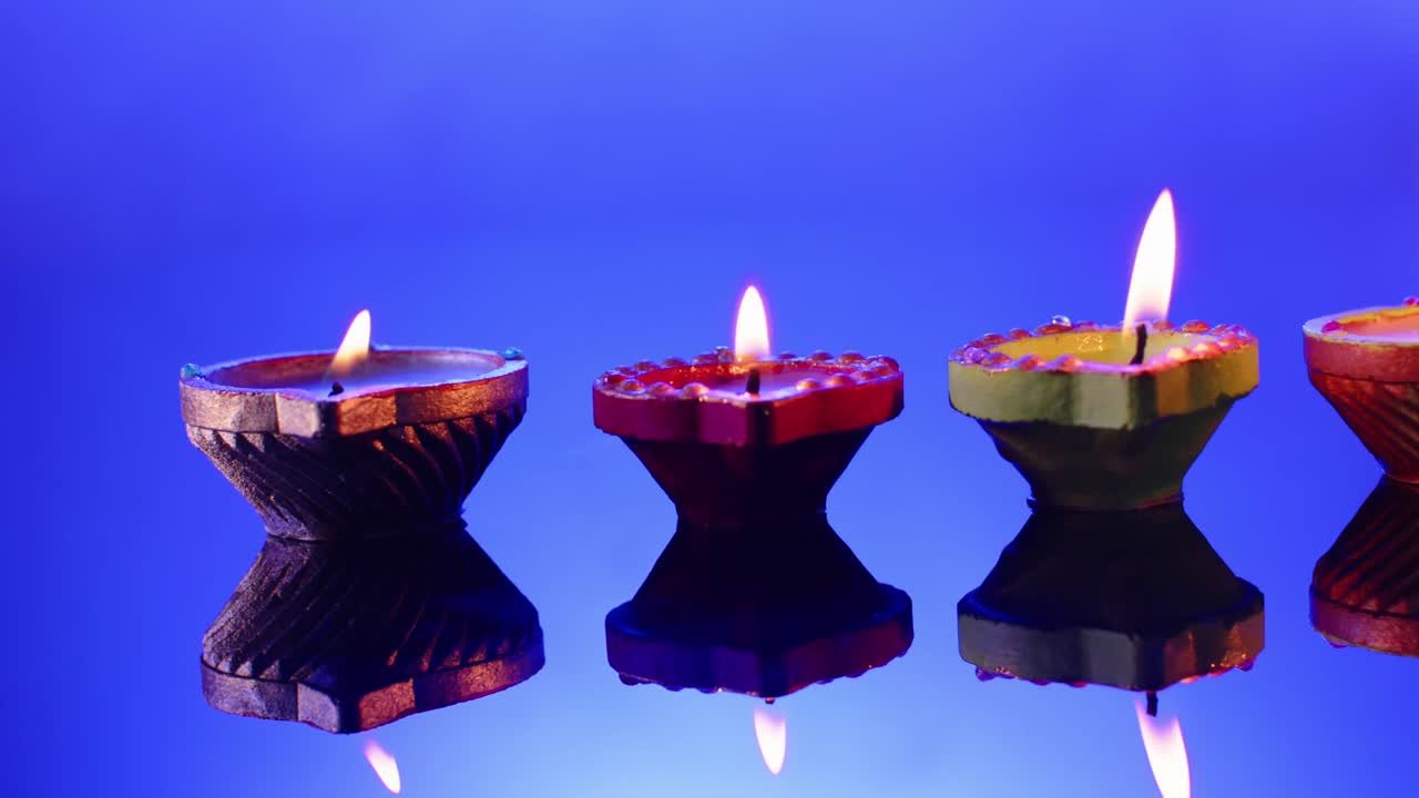 Primo piano di candele accese in fila che celebrano il Diwali su sfondo blu