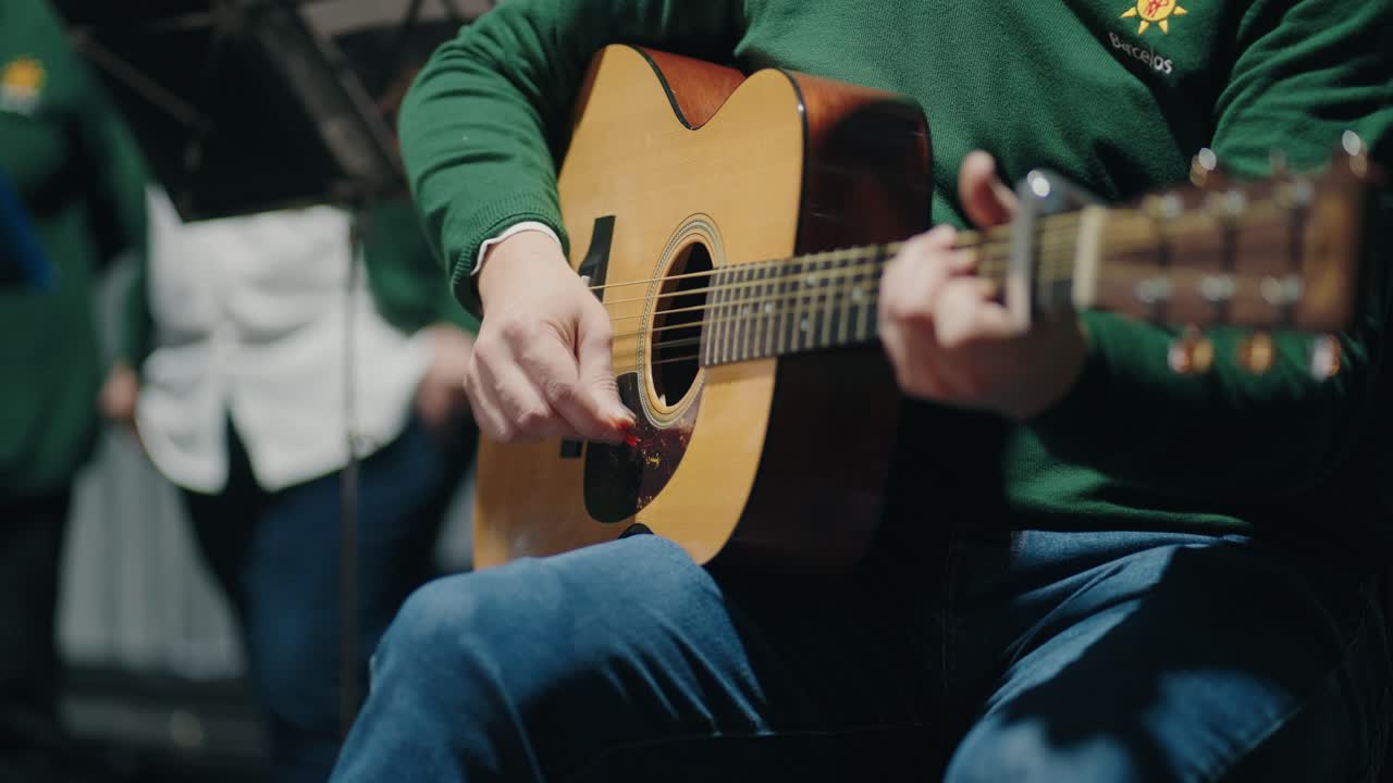 seated guitarist strumming an acoustic guitar at a live music performance