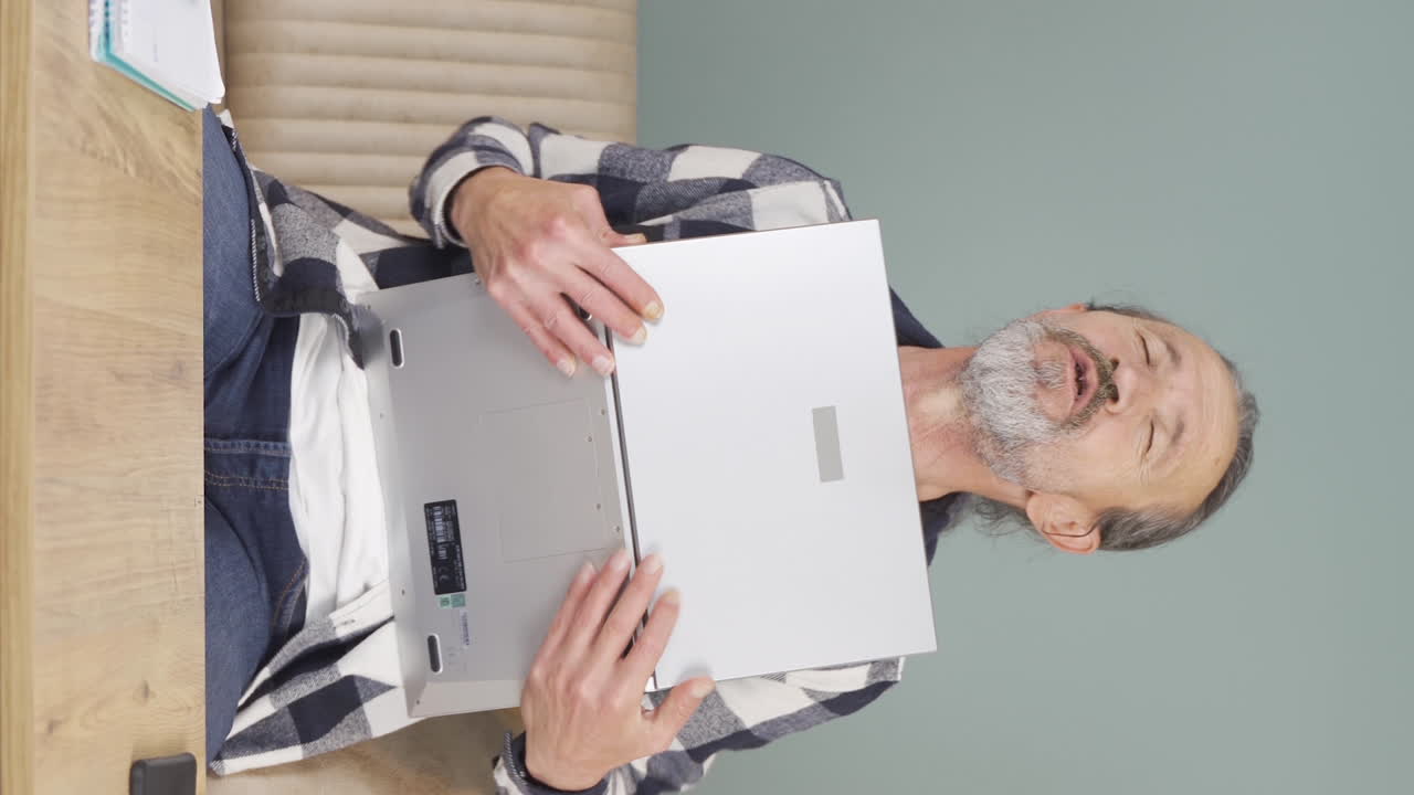 video vertical del anciano abrazando alegremente la computadora portátil.