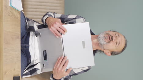 video vertical del anciano abrazando alegremente la computadora portátil.