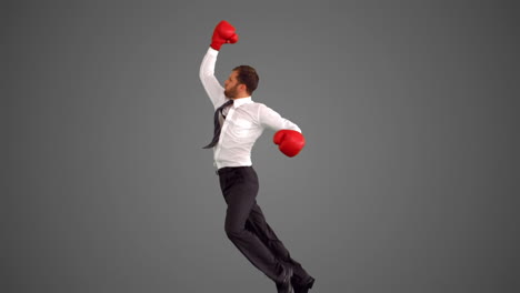 Businessman-in-boxing-gloves-leaping-and-punching-on-grey-background