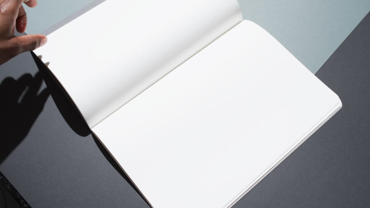 Video of hand of african american man holding book with blank pages, copy space on black background