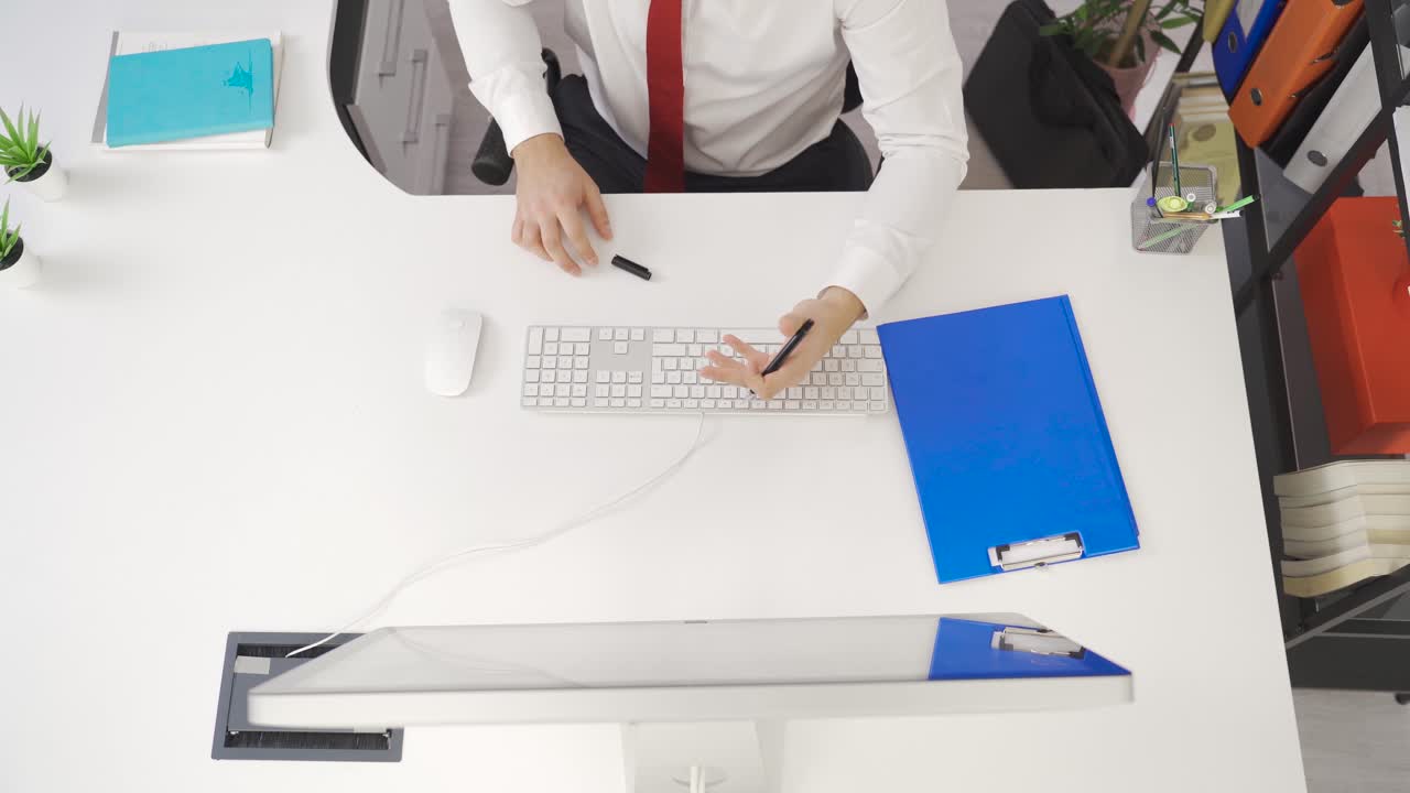 Professionel kreativ mand arbejder ved computeren ved sit skrivebord på kontoret, skriver noter, foretager telefonopkald
