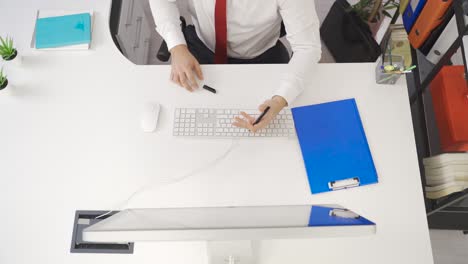 hombre creativo profesional trabajando en la computadora en su escritorio en la oficina, escribiendo notas, llamadas telefónicas.