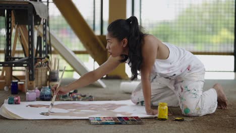 woman painting on the floor in an art studio