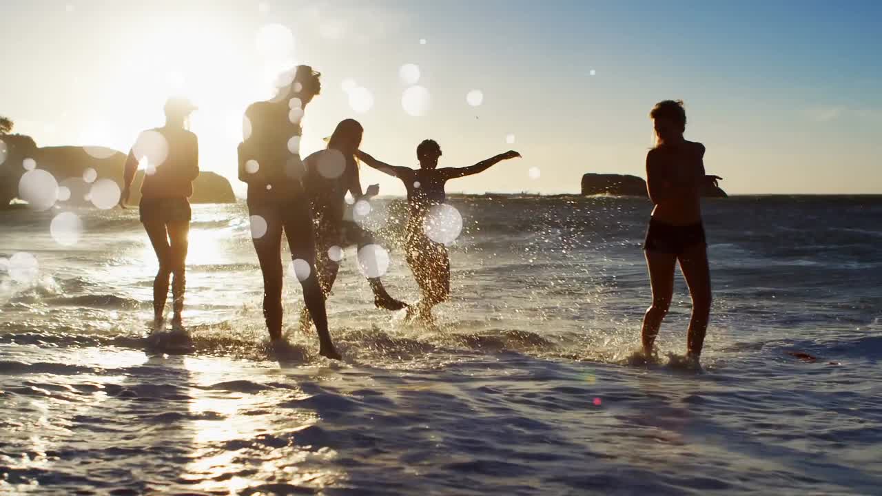 Donne che giocano in spiaggia al tramonto tra bolle bianche.