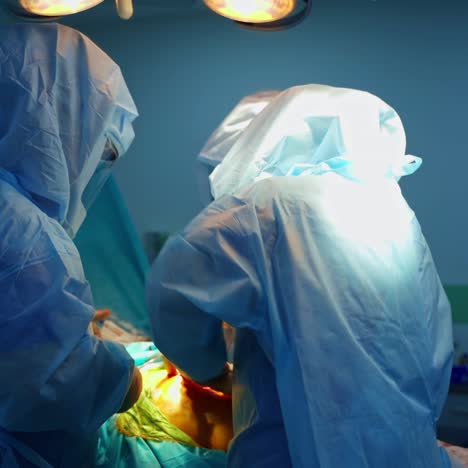 professional surgeons with medical tools. group of medical specialists in safety suits perform a surgery to patient in operating room.