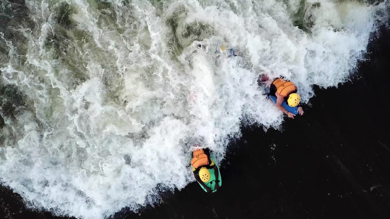 Veduta aerea dall'alto di un bodyboarder che aiuta un altro bodyboarder a prendere un'onda sul fiume Nilo a Jinja, Uganda.