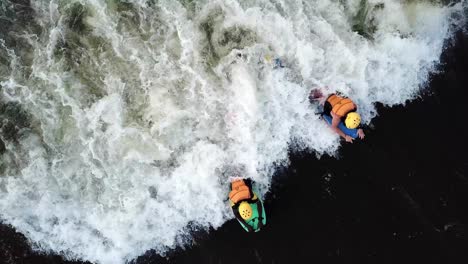 Vista-Aérea-Desde-Arriba-De-Un-Bodyboarder-Ayudando-A-Otro-Bodyboarder-A-Atrapar-Una-Ola-En-El-Río-Nilo-En-Jinja,-Uganda