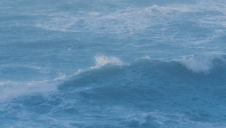 beautiful rough stormy blue sea waves breaking with seagull flying over in high winds in slow motion. powerful turbulent surf swell in beach bay in england during storm darragh 4k.