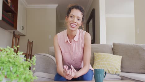 Happy-biracial-woman-sitting-on-sofa-and-having-video-call