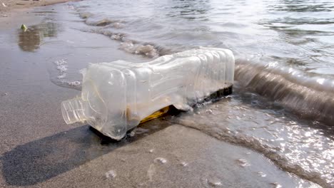 Ocean-plastic-pollution-debris,-clear-plastic-water-bottle-washes-up-from-the-ocean-onto-the-beach-of-remote-tropical-island