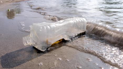 Escombros-De-Contaminación-Plástica-Del-Océano,-Botella-De-Agua-De-Plástico-Transparente-Se-Lava-Desde-El-Océano-Hasta-La-Playa-De-Una-Isla-Tropical-Remota