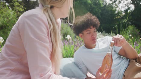 pareja feliz y diversa haciendo picnic en el jardín en un día soleado