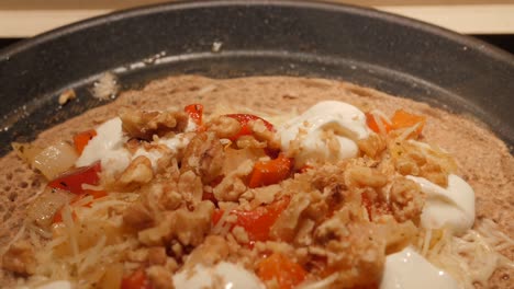 french buckwheat crepe with toppings cooking on a non-stick pan