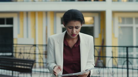 Disappointed-business-woman-examining-documents-outdoors.-Sad-lady-feeling-upset