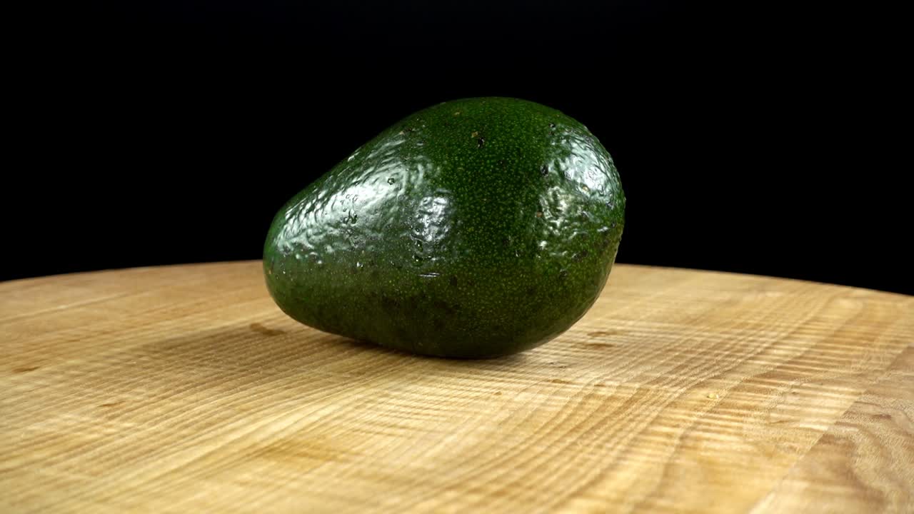 Avocado su sfondo nero. Tagliere in movimento.