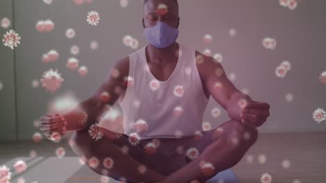 covid-19 cells floating against african american man wearing face mask practicing yoga