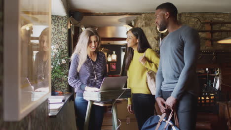 receptionist handing guest couple key as they check into hotel