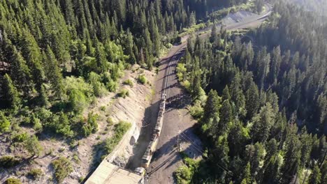 disparo de drones moviéndose hacia atrás mientras un tren en primer plano sale de un túnel con colores brillantes y cielo azul