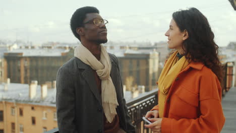 Diverse-Man-and-Woman-Chatting-on-Rooftop-Terrace