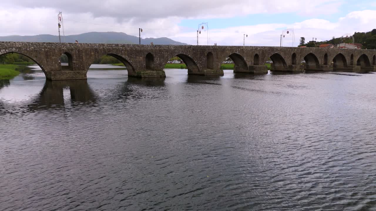 Roman Bridge in Ponte de Lima with clouds and calm water, serene scene