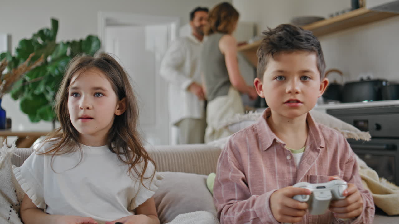 Excited siblings video gaming having fun together home closeup. Boy girl playing