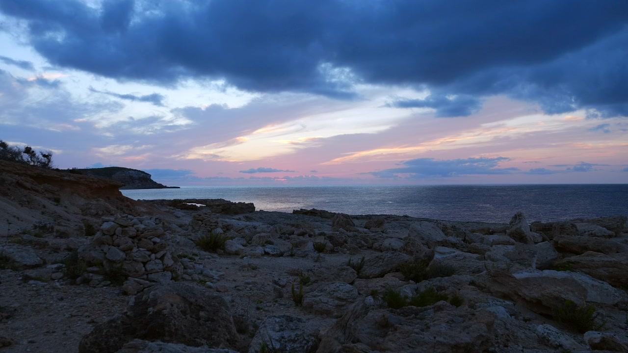 Praia de enseada rochosa ao anoitecer em Portinatx, Ibiza, Espanha. Plano geral.