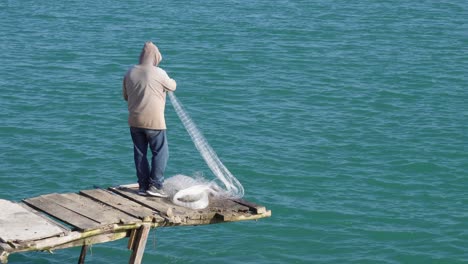 fisherman retrieving his net on a pier