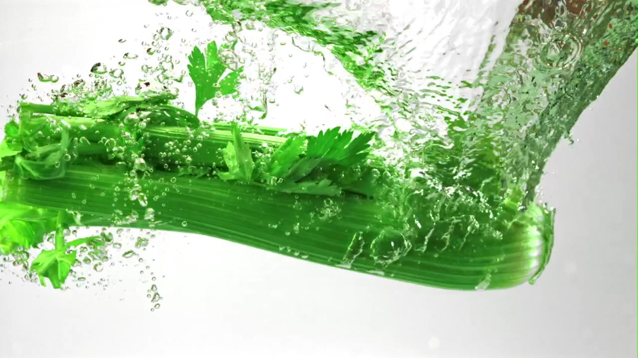 Fresh Green Celery Dropping into Clear Water with Splashes