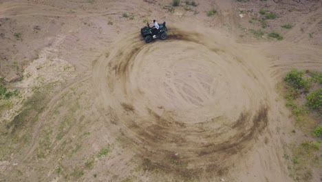 un hombre conduciendo un quad motor en un círculo.