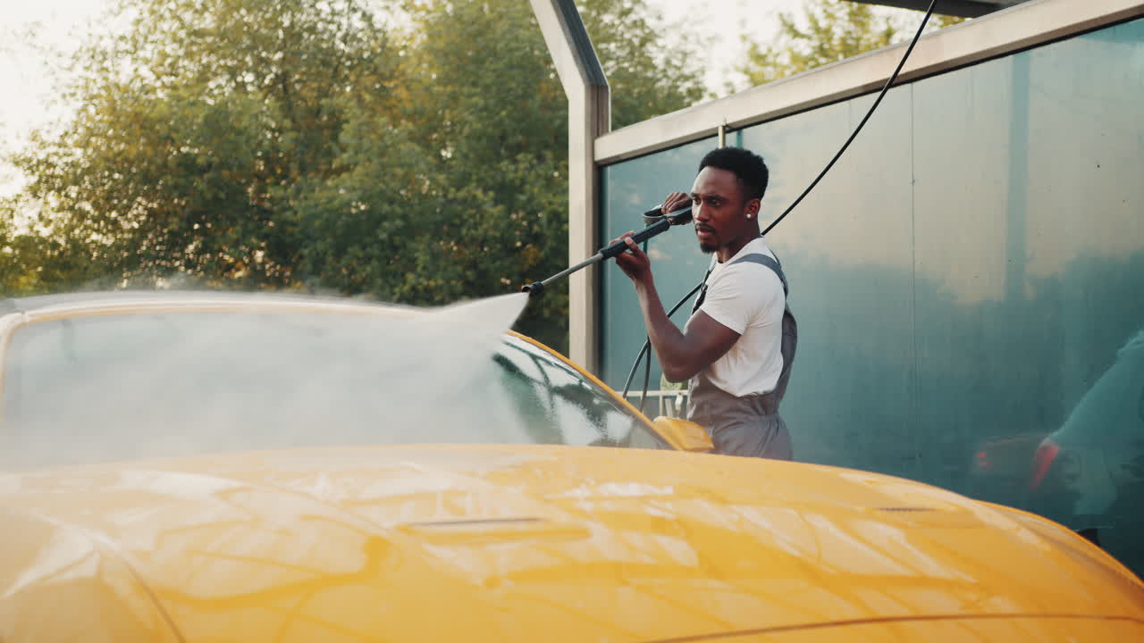 남자가 야외 세탁소에서 노란색 차를 고 있다