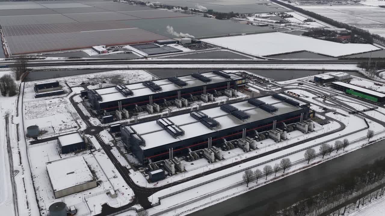 Aerial drone video of a large-scale computing and datacenter facility in winter, showcasing telecommunications infrastructure, server systems, and high-capacity digital operations