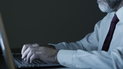 hombre de negocios maduro trabajando con computadora en una oficina oscura