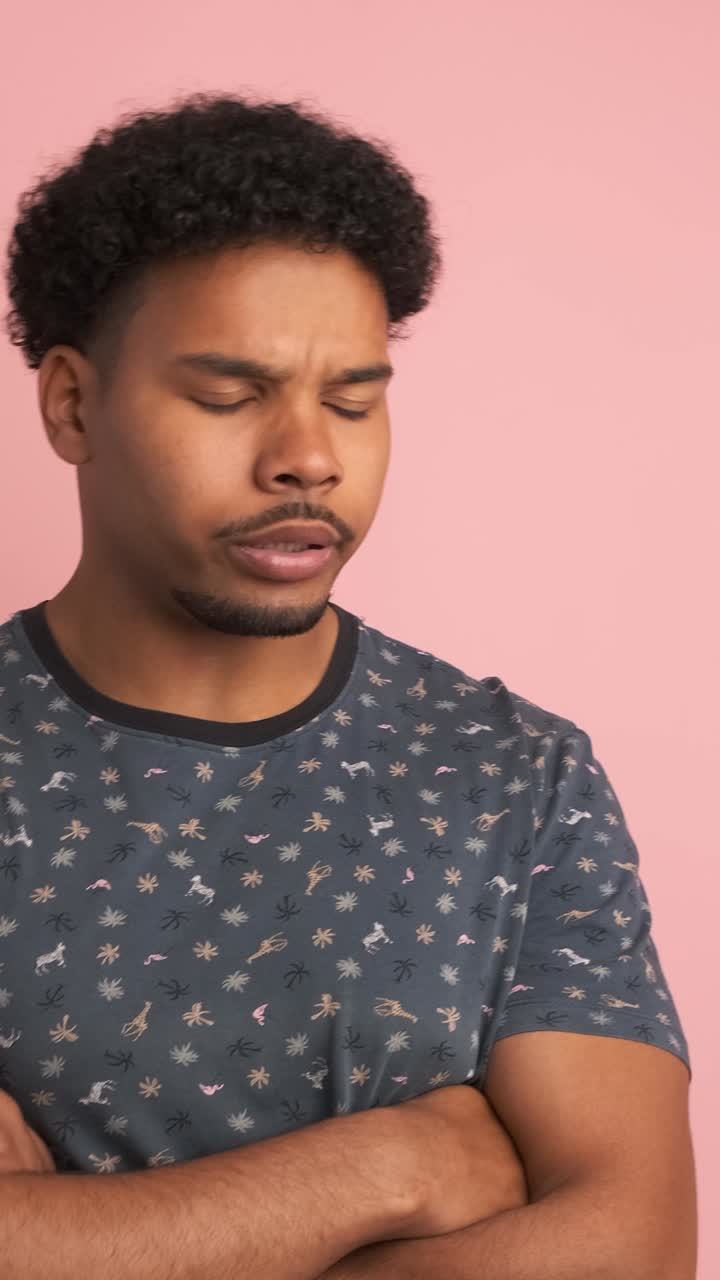 Disagreeing young man shaking head in pink studio