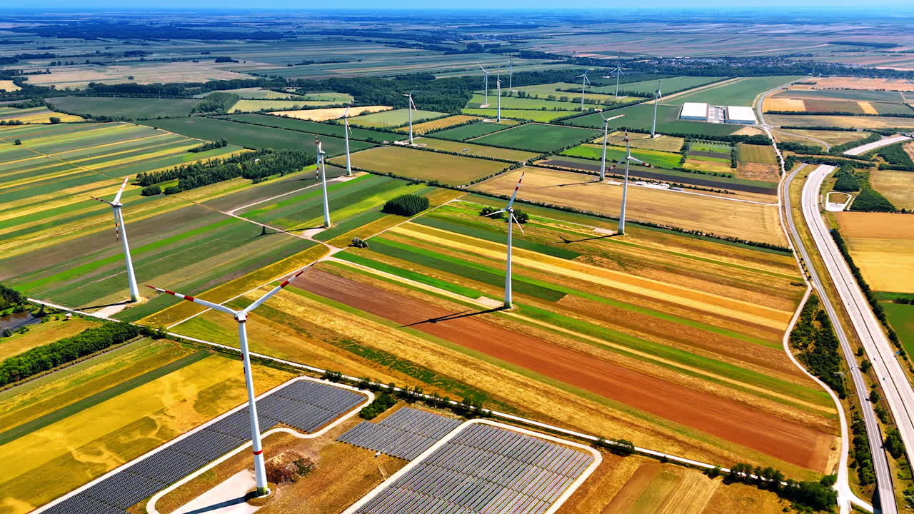 Flying over the endless fields on summer day. Wind turbines and solar panels installed in the countryside to produce green power