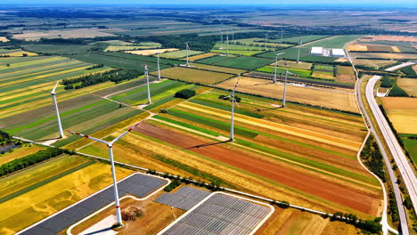 flying over the endless fields on summer day. wind turbines and solar panels installed in the countryside to produce green power