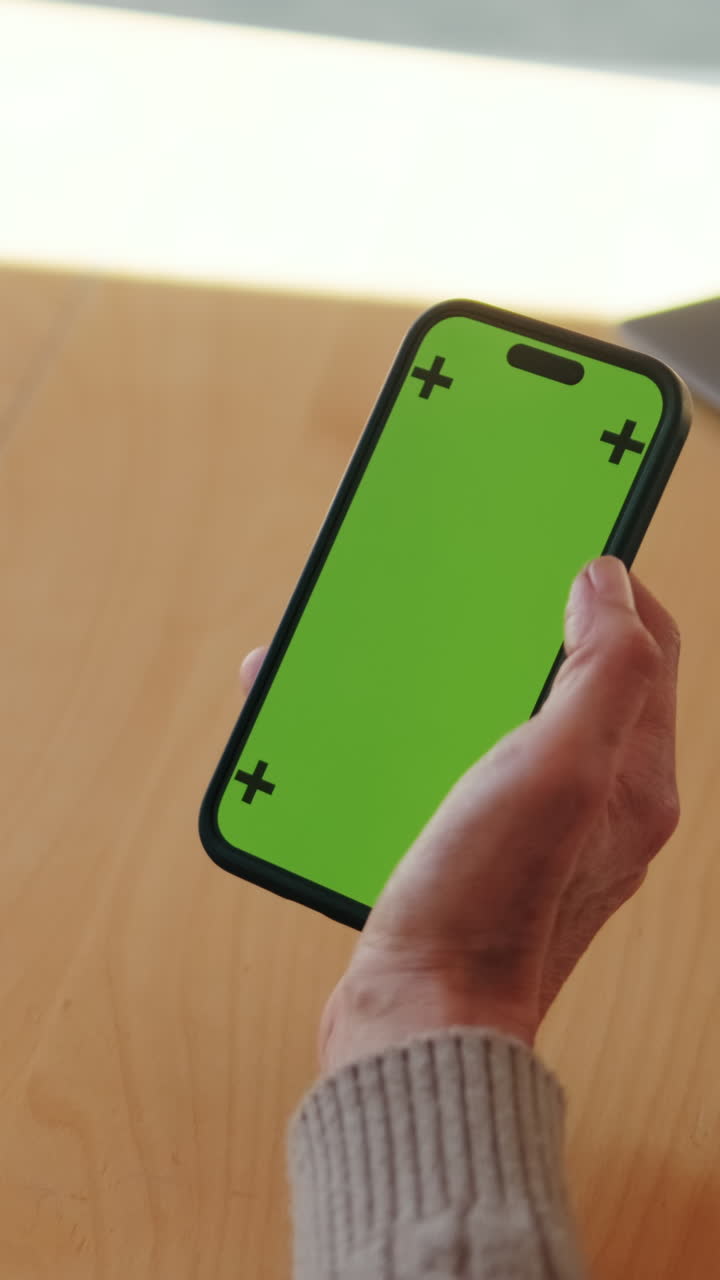 Persona che tiene uno smartphone con schermo verde