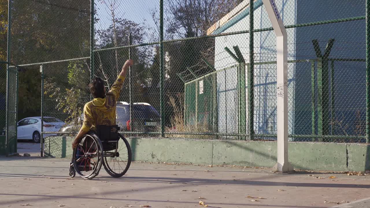 joven discapacitado en silla de ruedas jugando al baloncesto al aire libre.