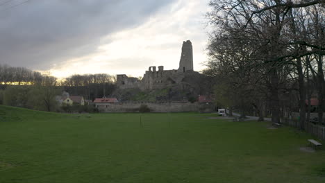 Park-and-road-lined-with-trees-leading-to-ruined-Okoř-castle-at-sunset