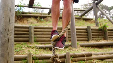 Low-section-of-man-climbing-a-rope-during-obstacle-course-4k