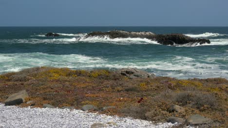 una pequeña isla frente a la costa golpeada por las olas en la costa atlántica con un primer plano rocoso