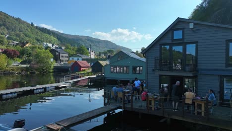 guests dine outdoors by the fjord at mjoesvagen seafront restaurant, enjoying the waterfront view in shaded seating