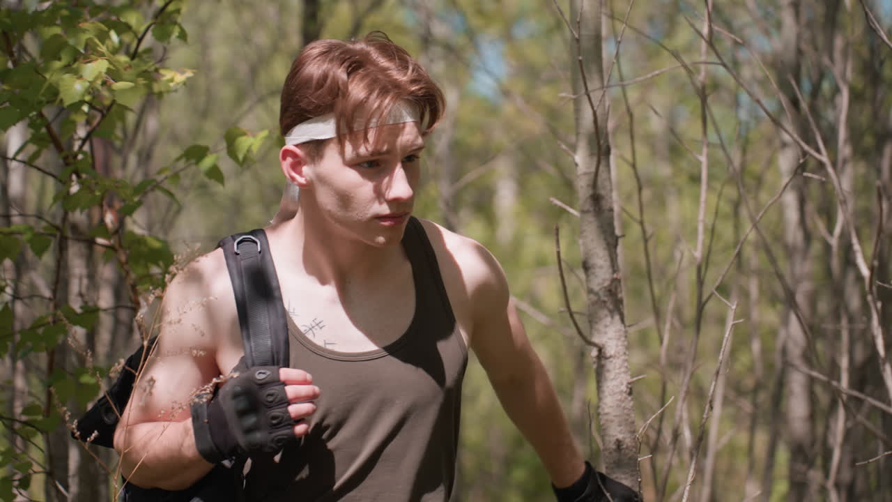 front view of warrior walking through dense woodland using bare branches for support while scanning surroundings under dappled sunlight among birch trunks, leaves rustling in gentle breeze