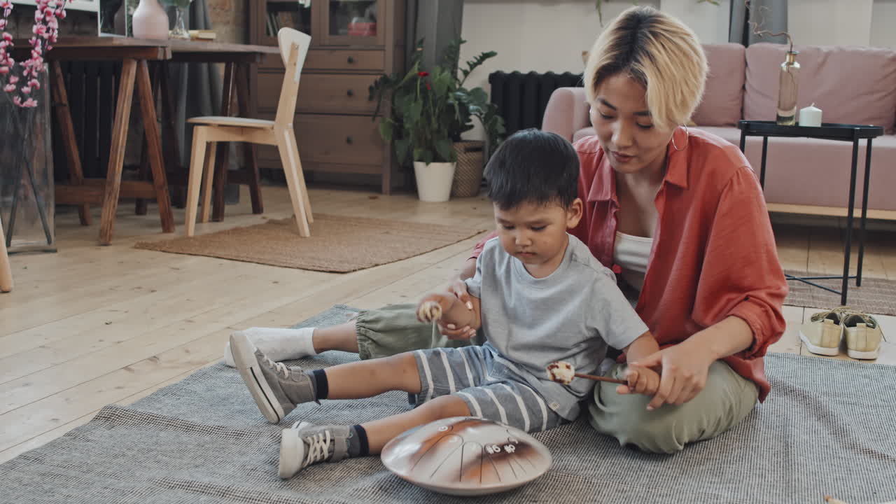 Asian Woman Teaching Son to Play Glucophone